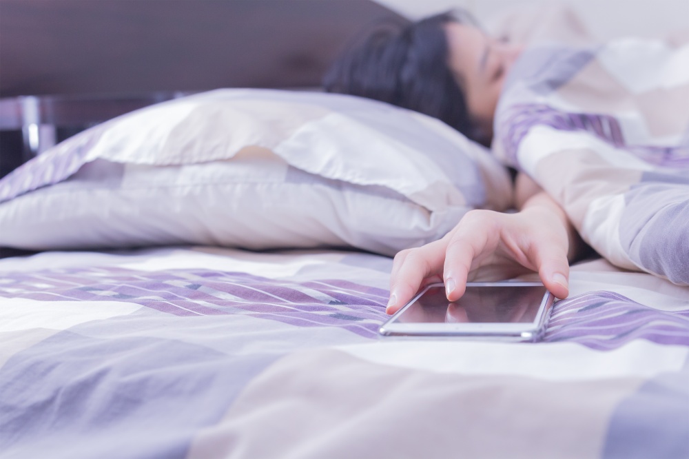 Woman sleeping in bed being woken by mobile phone